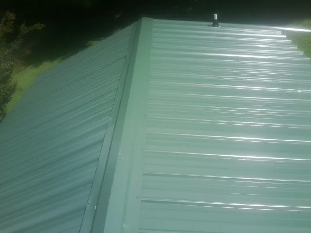 New green metal panels meeting at the ridge of a roof — Flat Roof Repair work by our crew in Landisville