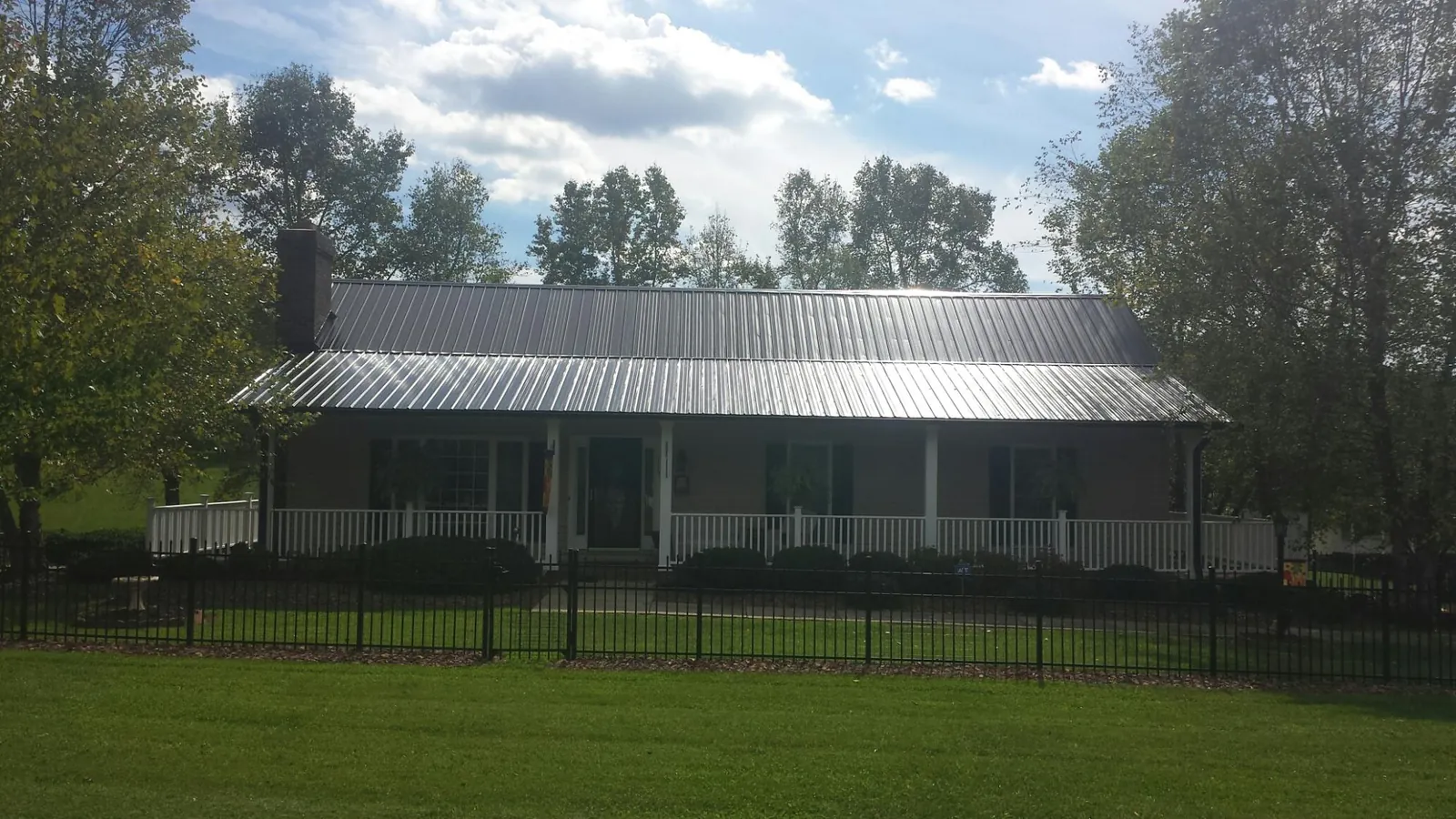 Gray metal roof on a brick ranch with a full width front porch — Gutter Guard Installation work by our crew in Landisville