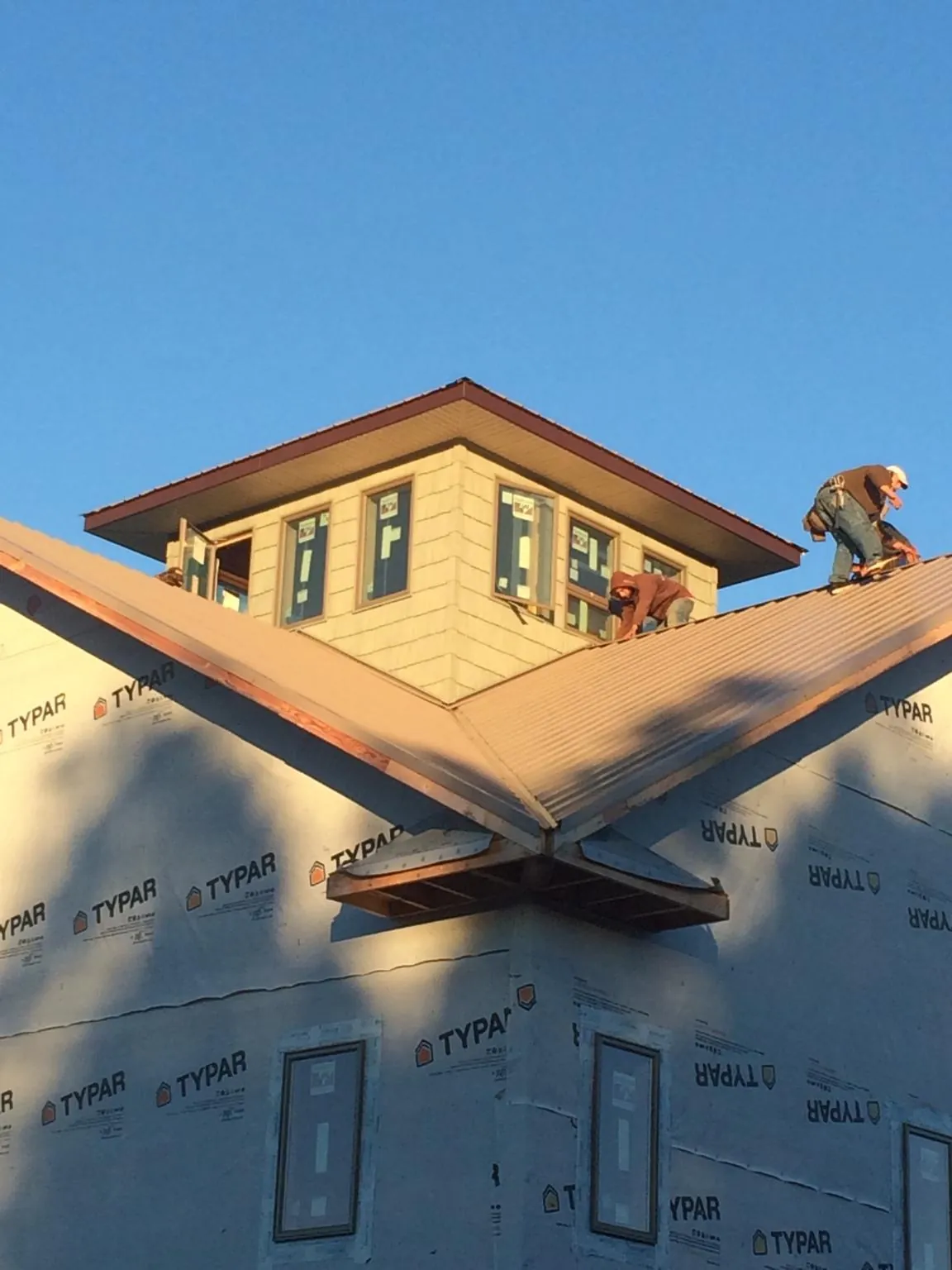 Roofers working around a rooftop cupola on a new metal roof at sunset — Roof Waterproofing in Landisville by Roofing Brothers